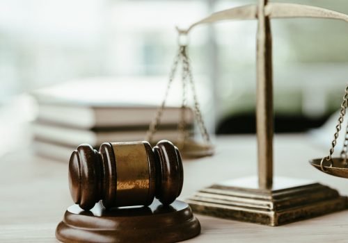 Martelo de juiz (gavel) de madeira e balança da justiça dourada sobre mesa de escritório, representando decisões em processos de direito trabalhista.