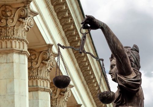 Estátua da Justiça segurando balança em frente a tribunal clássico, simbolizando a busca por benefícios do INSS e direitos no Direito Previdenciário.