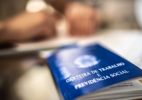 Carteira de Trabalho (CTPS) sobre mesa de madeira, representando direitos como FGTS, férias e horas extras.